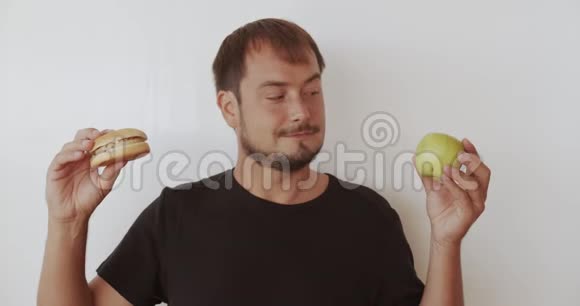 男人选择健康或不健康的食物在苹果和汉堡之间做出选择的人无论是健康的还是快的垃圾食品都选择了视频的预览图