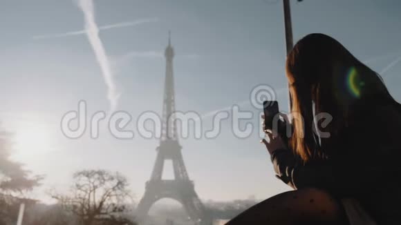 快乐的年轻旅游女性用智能手机慢动作拍摄史诗般的日落巴黎埃菲尔慢动作视频的预览图