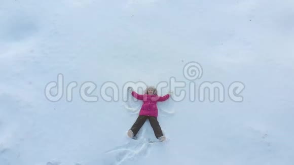 快乐的小女儿在雪地里做天使快乐有趣的童年在阳光明媚的冬日户外视频的预览图
