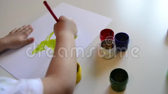 小男孩的手在纸上画画可爱的孩子坐着画画呆在家里视频的预览图
