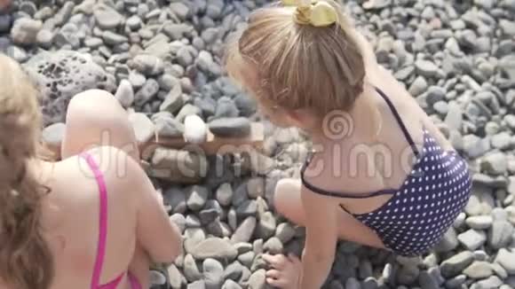 穿着泳衣的小女孩在海边的鹅卵石海滩上玩耍视频的预览图