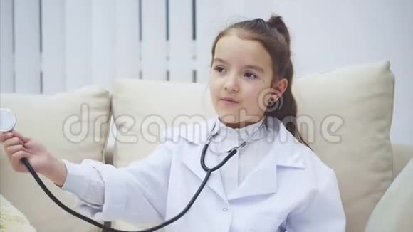 有趣的女孩坐在沙发上耳朵里有听诊器在检查空气中的东西视频的预览图