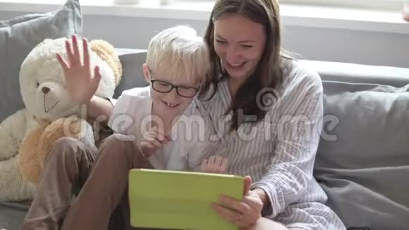 妈妈和儿子坐在沙发上手里拿着一块平板电脑视频的预览图