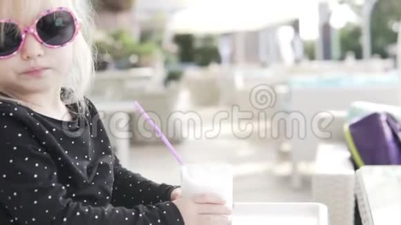 时髦的婴儿在户外咖啡馆喝一杯稻草做的香草奶昔视频的预览图