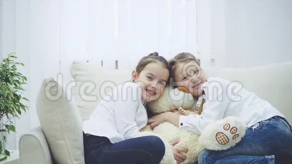 两个可爱的快乐女孩在玩泰迪熊拥抱他们毛绒朋友微笑看起来可爱视频的预览图