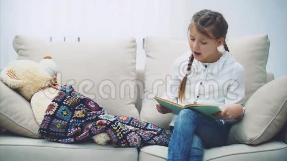 漂亮的小女孩为她的泰迪熊读童话故事抚摸它合上书享受晚安睡着了视频的预览图