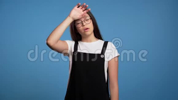 沮丧无聊的亚洲女孩越过蓝墙背景女人厌倦了工作或学习她失望无助视频的预览图
