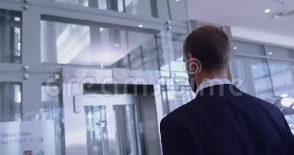 在现代化办公室的走廊里等电梯的商人视频的预览图