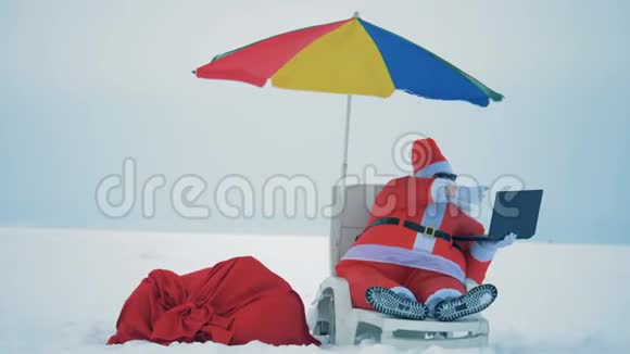 带着圣诞老人坐在一张躺椅上做一个视频游戏的雪景视频的预览图