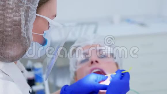 牙科医生对年轻女性进行超声波清洗后的牙齿进行氟化处理视频的预览图