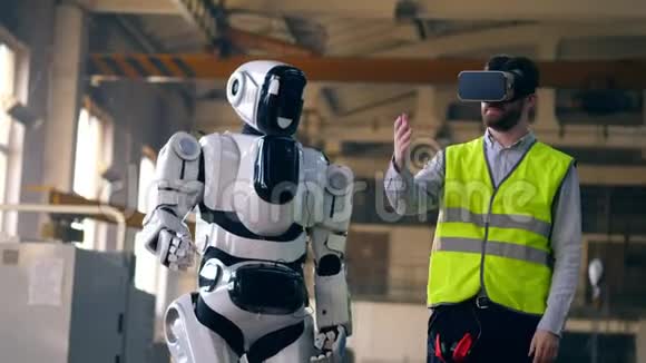 一个戴VR眼镜的人用白色机器人工作视频的预览图