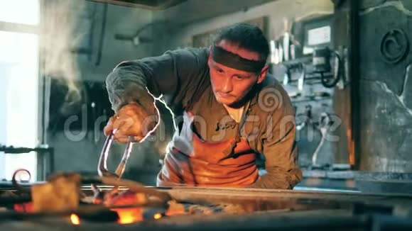 一个铁匠用钳子拿着热刀视频的预览图