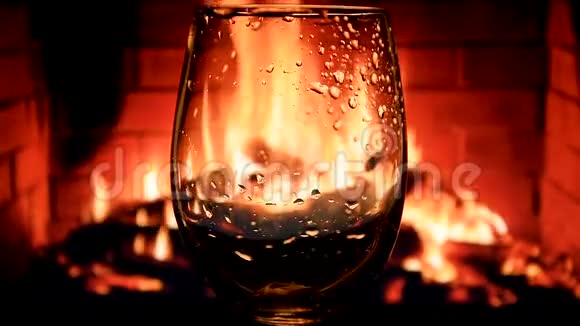 在壁炉背景下缓慢地将白葡萄酒从瓶子倒入酒杯中葡萄酒的美丽库存镜头视频的预览图