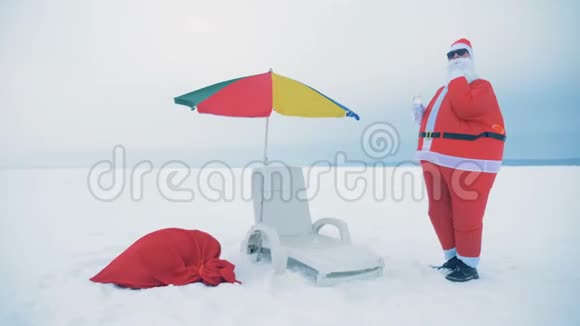 圣诞老人正在一张躺椅和一把伞附近喝酒跳舞视频的预览图