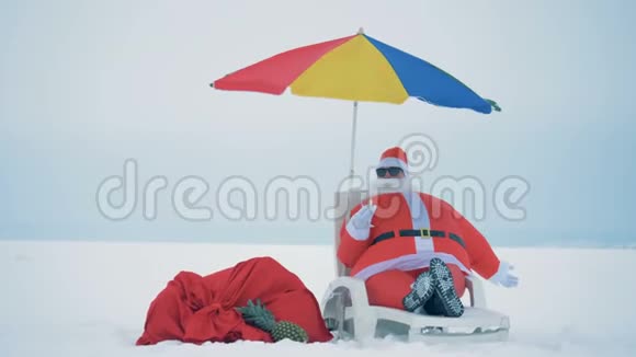 圣诞老人坐在甲板椅上喝香槟放松视频的预览图