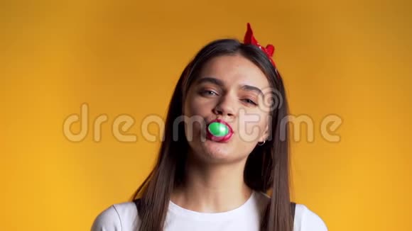 黄墙上嬉戏的女孩吹泡泡糖慢吞吞地嚼着绿口香糖视频的预览图
