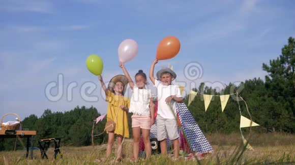 快乐的童年朋友男孩和女孩在孩子们的野餐中快乐在森林草地上跳跃和释放球对抗视频的预览图