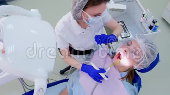 牙科医生用餐巾纸擦拭女性病人的面部在临床上进行超声清洗视频的预览图