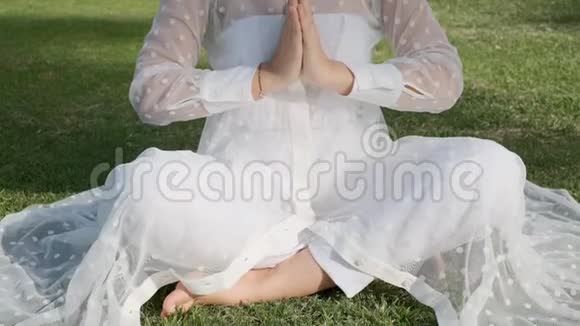 在阳光明媚的一天女人在公园里冥想做瑜伽慢动作特写视频的预览图