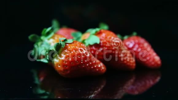 特写镜头集中在一组新鲜成熟多汁的红色草莓上放在黑色上视频的预览图