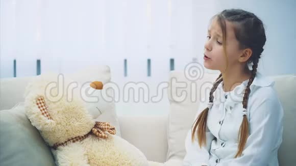 可爱的小女孩坐着和她的泰迪说话斥责它摇动她的手指折叠手转向一边视频的预览图