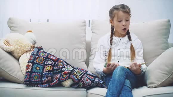 漂亮的小女孩为她的泰迪熊读童话故事抚摸它说晚安视频的预览图