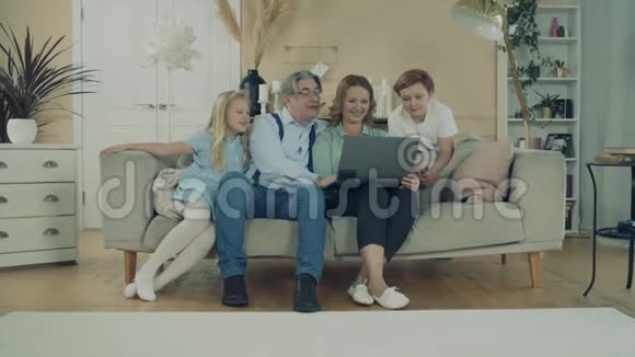 快乐的孩子和他们的祖父母用笔记本电脑视频的预览图