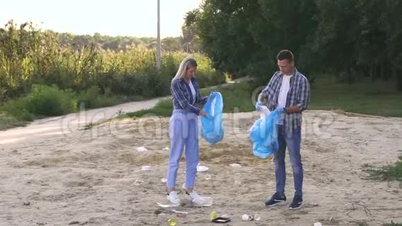 戴手套的女人和男人正在湖边的公园里打扫海滩视频的预览图