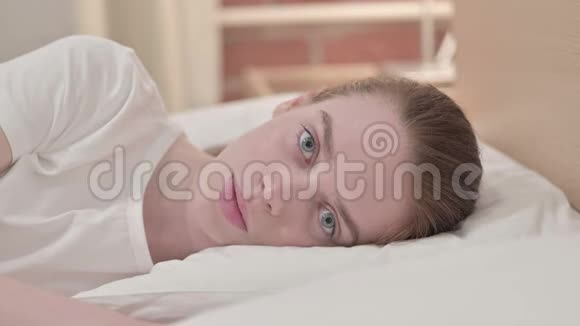 迷人的红头发年轻女人想睡在床上视频的预览图