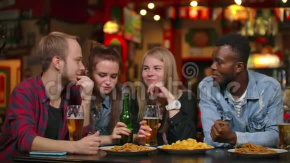 一个由7个男女朋友组成的多民族公司笑着喝啤酒做祝酒视频的预览图
