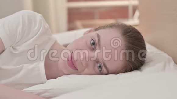 快乐的红发少女在床上微笑视频的预览图