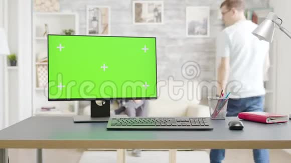 在明亮的客厅里桌上装有隔离绿色屏幕模型的电脑视频的预览图