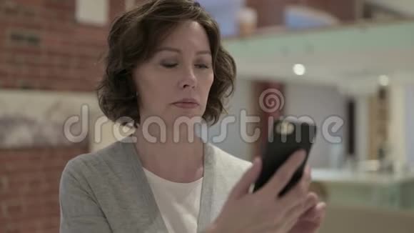 愤怒的老女人在智能手机上尖叫的画像视频的预览图