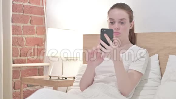 在床上谈论智能手机的年轻人视频的预览图