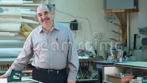 一位资深男企业主站在他的车间柜台后面对着摄像机微笑的画像视频的预览图