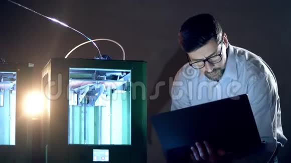 一个有笔记本电脑的人控制3D打印机三维印刷行业研究工程师在实验室工作视频的预览图