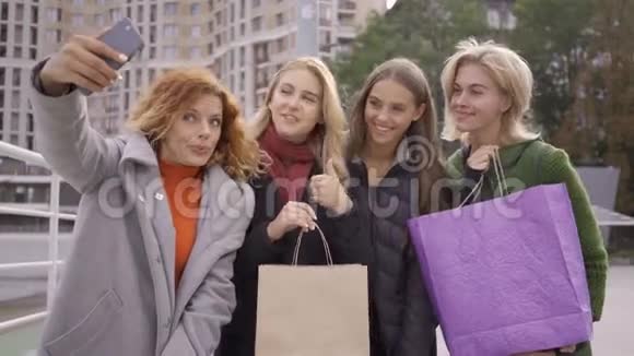 四个快乐的朋友带着购物袋和自拍城里四个时尚女人一起休闲女孩视频的预览图