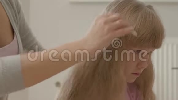 年轻女子的特写手梳着她可爱的金发女儿母亲的概念童年室内休闲快乐视频的预览图