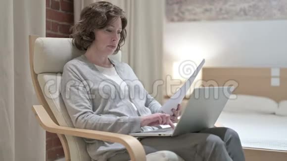 旧女人在沙发上用笔记本做纸工视频的预览图