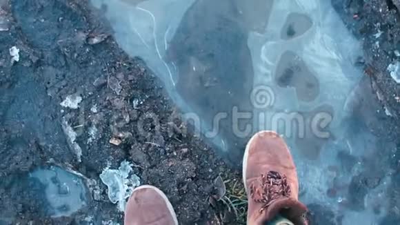 一个男人穿着靴子穿过冰冻的水坑视频的预览图