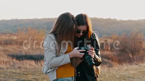 两名女游客正在拍照时用数码相机浏览照片视频的预览图