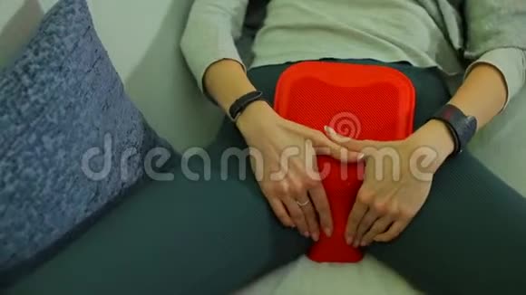 这个女孩在她的胃上放了一个温暖的加热垫以缓解PMS的症状视频的预览图
