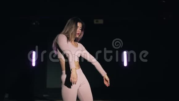 女孩在黑暗的背景下跳舞性感的舞蹈穿着诱人服装的女人随着音乐的节奏移动慢动作视频的预览图