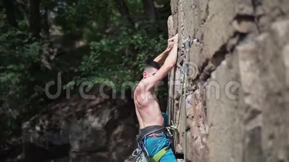 年轻的攀岩者赤裸的躯干爬在花岗岩悬崖上紧握着但坠落视频的预览图
