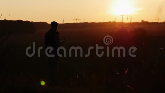 日落时分男子控制着乡村的四架飞机无人机在田野里拍照视频的预览图