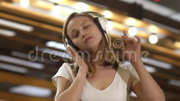 年轻漂亮的女人在耳机里欣赏音乐视频的预览图