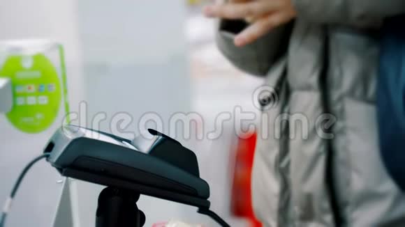 一个女人在结账的超市用智能手机付款使用现代和方便的NFC无线支付视频的预览图