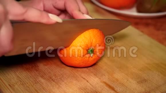 木板上的女孩用刀切开一种成熟多汁的维生素橙视频的预览图