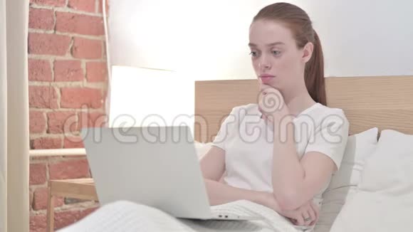 红头发青年妇女在床上思考与工作视频的预览图