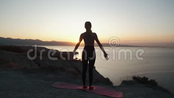 日出时女性在山顶练习瑜伽动作缓慢视频的预览图